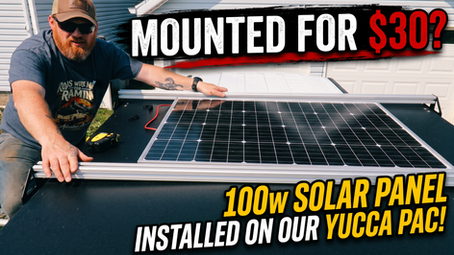 Dan mounting a 100W solar panel between the roof rack rails of a Yucca-Pac Safari camper.