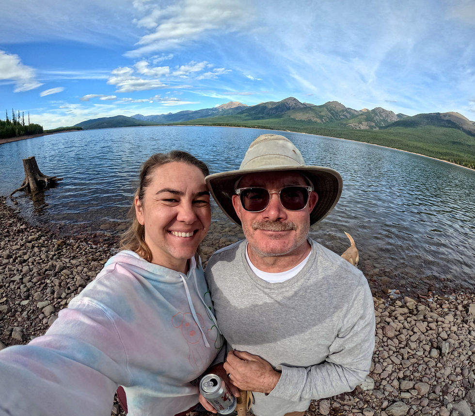 Man and a woman In front of a lake surrounded by mountains