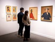 Two visitors view framed portraits in a gallery at The Whyte featuring When our eyes touch exhibition, with white walls and gray carpet.