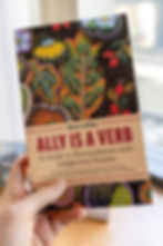 Hand holding Rose LeMay’s book Ally Is a Verb, a guide to reconciliation with Indigenous Peoples, on a colorful beadwork cover.