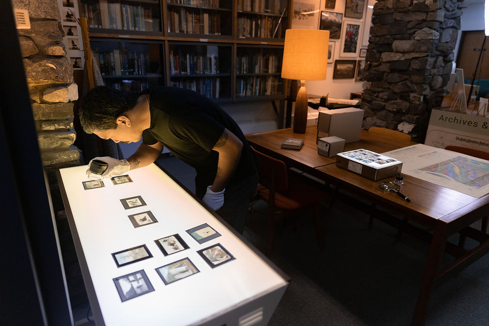 Researcher examining lantern slides in the Archives and Special Collections library at The Whyte in Banff, Alberta.