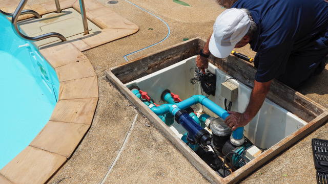 Professional pool technician repairing residential pool pump and filtration equipment
