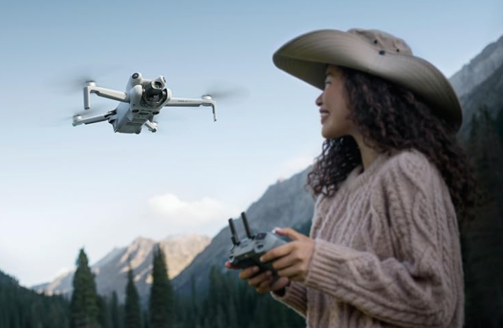 A beautiful woman with a hat flying a DJI Mini drone