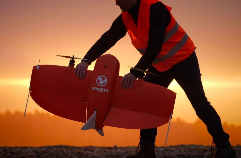 Construction Worker in an orange vest lifting an orange Wingtra Drone