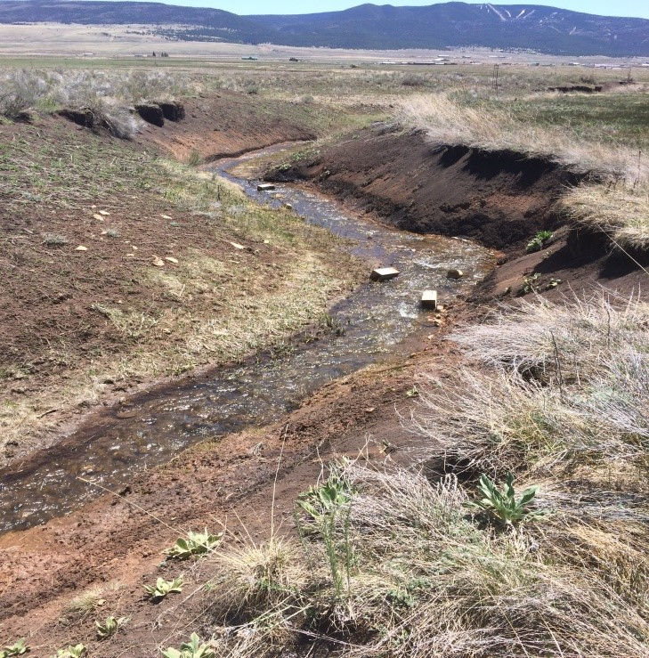 stream cutting through field of dirt