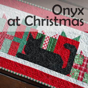 Onxy at christmas table runner featuring a black cat in front of gift-wrapped presents