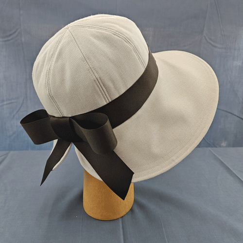 the back view of a pale grey garden-tea hat with a contrasting black ribbon bow at the back