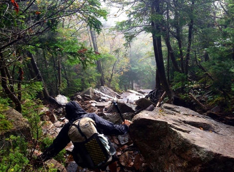 Colton hiking the Appalachian Trail in the White Mountains of New Hampshire, hyperlite mountain gear backpack and going down steep boulders