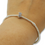 Thumbnail: Dog or Cat Paws Bead Charm in sterling silver. Circle shaped bead with 2 paws on the outer edge.  Clear jewels in the paws. Shown on a silver bracelet on a persons wrist.