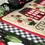 Thumbnail: Strawberry cross stitch pattern stitched example. Embroidery thread in red, green, white, and black used in the pattern.