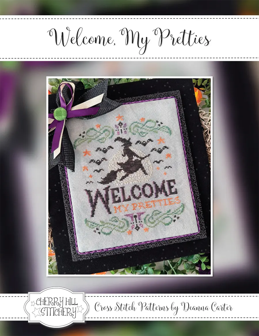 Halloween counted cross stitch pattern cover. The witchy cross stitch design is called "Welcome, My Pretties" and was designed by  Cherry Hill Stitchery® . There is a witch silhouette in front of a full moon, surrounded by bats. There is a spooky green border with whimsical purple candles and orange stars. The design is stitched in green, purple, orange, and black. The stitched model has text "Welcome, My Pretties" on gray cross stitch cloth.
