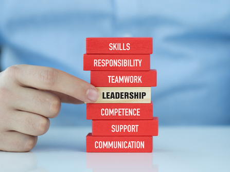 A man is pointing to the word leadership which is in the middle of some of some stacked.