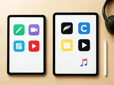 Two tablets on a wooden desk with colorful app icons. A pencil, keyboard, and headphones are nearby, creating a tech-focused workspace.