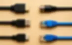 Various cables lie parallel on a wooden surface: HDMI, coaxial, USB, micro USB, and Ethernet, showcasing different tech connectors.
