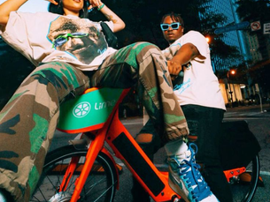 a woman on a red bike in front of a man, both posing on the bike
