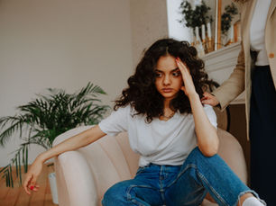 woman sitting in a chair looking overwhelmed with what the person behind them is telling them