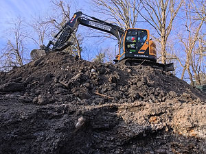 Excavator moving soil during foundation excavation at the Beverly Road new home project in Brookline