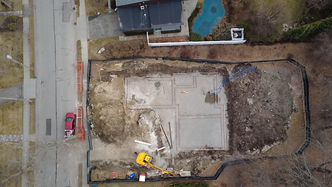Wide aerial view of foundation progress at the Beverly Road new home construction project in Brookline