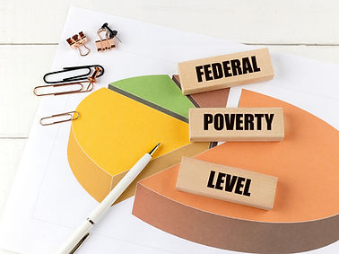 Federal poverty level text on wooden blocks placed on a pie chart with stationery and pen