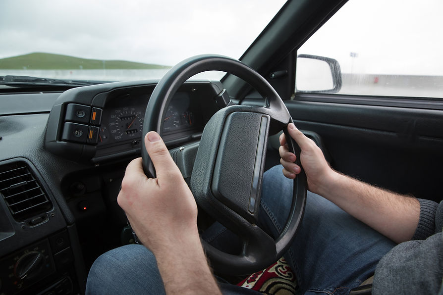 close-up image of a person's hand on steering wheel of a car