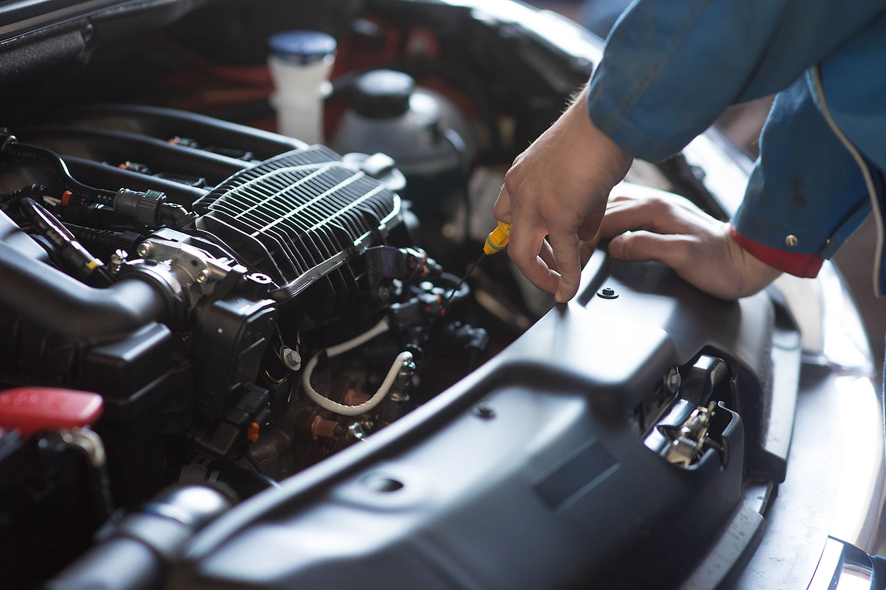 an auto mechanic's hand while inspecting car's engine oil