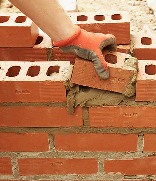Bricklayer inserts a half brick into a wall