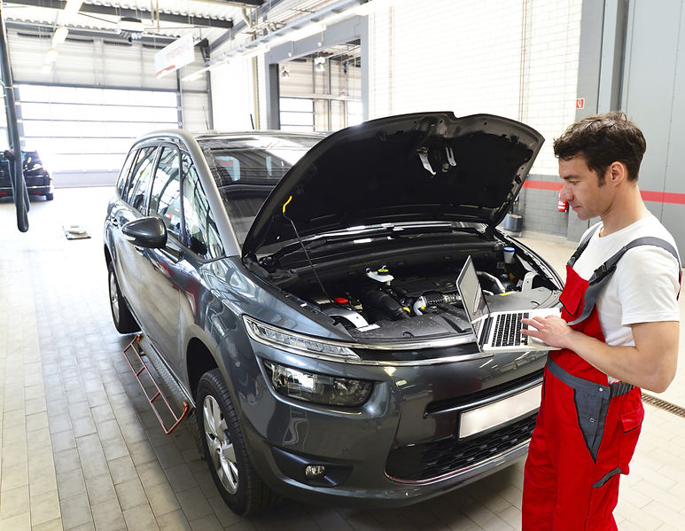 an auto mechanic using laptop in a garage