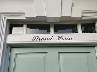 Green door with _Strand House_ in elegant script above