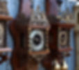 Ornate wooden clocks with intricate designs and metal details are displayed side by side