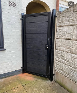 Black gate door with horizontal panels in a narrow outdoor space
