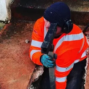 A man in an orange jacket holding a hammer