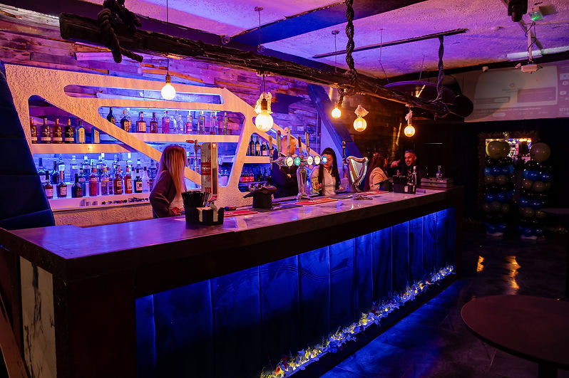 A bar interior featuring a sleek counter illuminated by vibrant blue lights