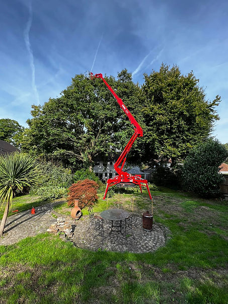 A red cherry picker stands stationary on a grassy field