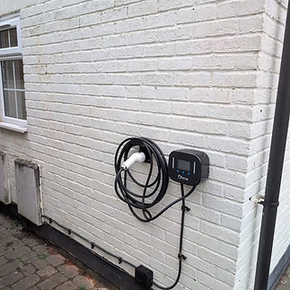 Electric vehicle charging station on a white brick wall of a house
