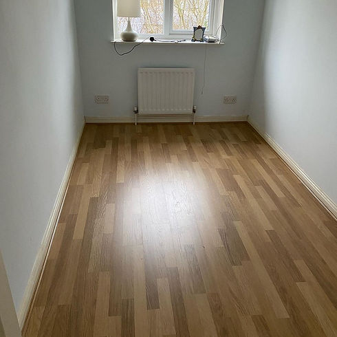 A small empty room with light wooden laminate flooring