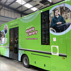 A green bus featuring a large image of a man prominently displayed on its side.