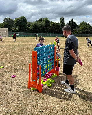 Children play a giant Connect Four game on a dry, grassy field