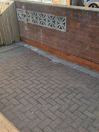 Brick driveway bordered by a red brick wall