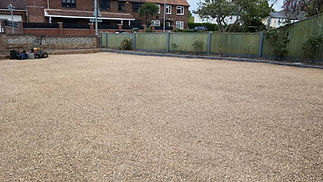 Gravel-covered yard bordered by a green wooden fence