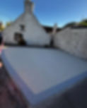 A concrete driveway leading to a white wall