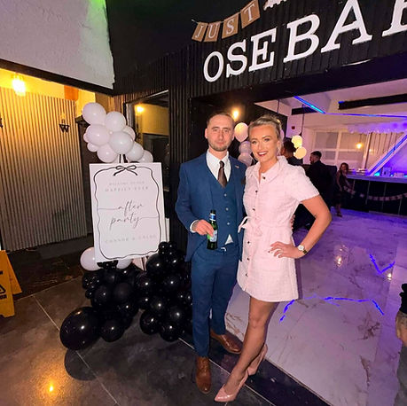 A man and woman stand together in front of a sign