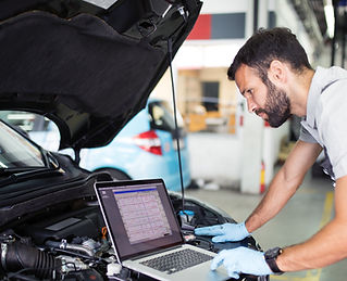 Technician checking a car engine with a laptop