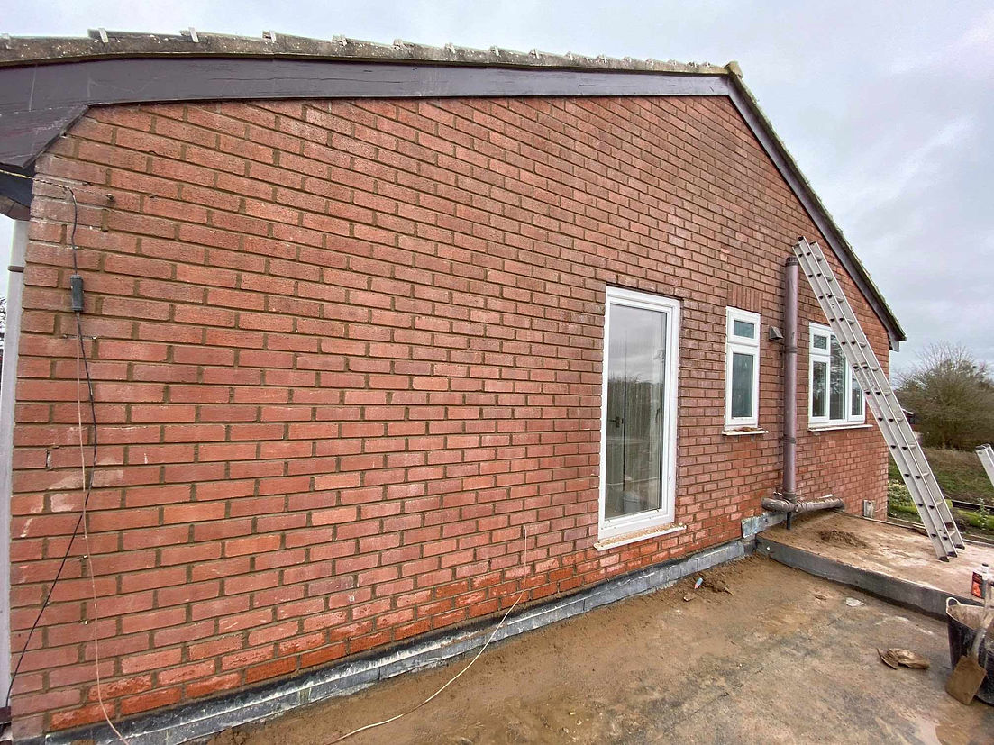 Straight brick wall of a house with three windows