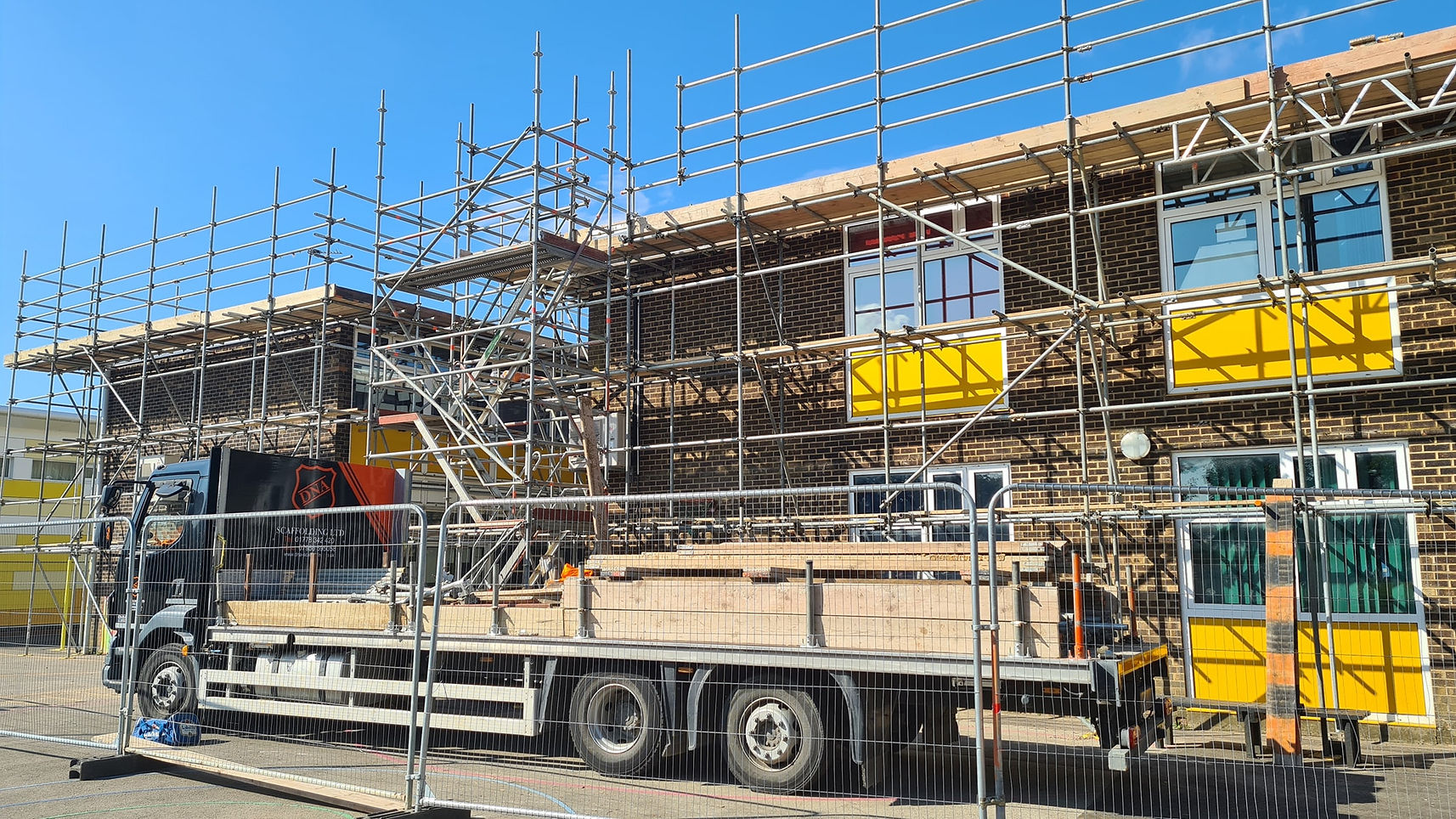 A construction site with scaffolding surrounding a brick building.