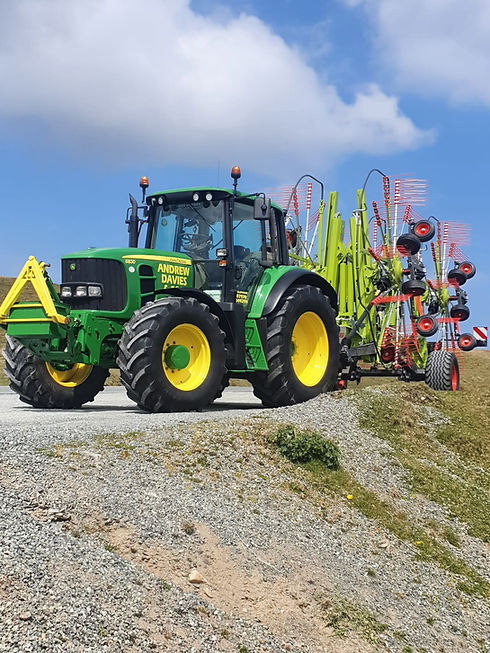 A tractor pulling a large green and red equipment across a field