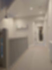 Bright hallway with white walls and carpet, featuring a staircase on the left.