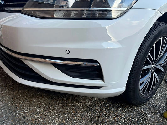Close-up of a white car's front bumper