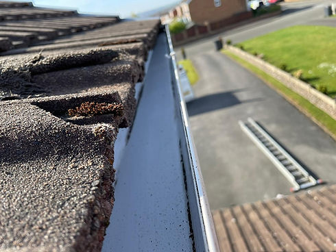 Close-up view of roof tiles and a clean gutter on a sunny day