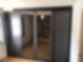 Modern bedroom with sleek dark wardrobe featuring mirrored sliding doors.
