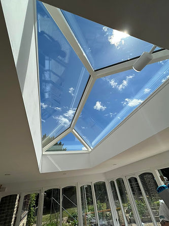 A large skylight in a bright room reveals a clear blue sky with scattered clouds.